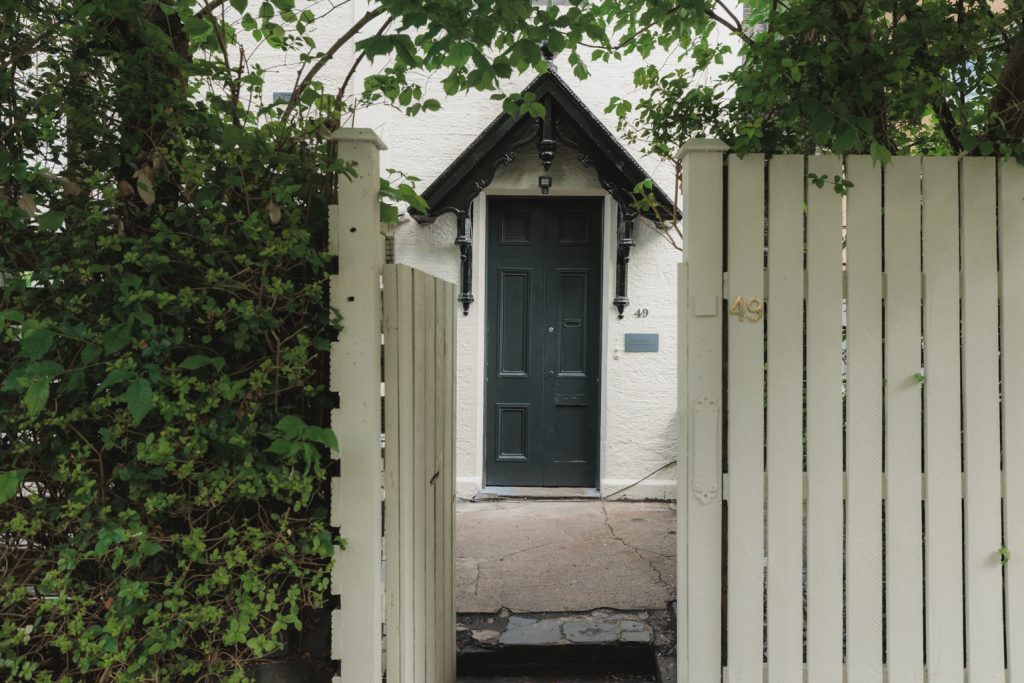Entrance to Janefield Cottage on Otago Street, featuring a traditional front door, decorative porch and secluded setting behind a private gate.