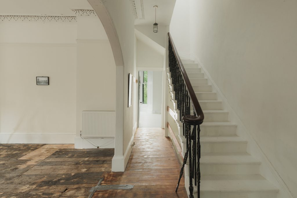 Original staircase and hallway within Janefield Cottage, featuring timber flooring, decorative cornicing and period architectural details.
